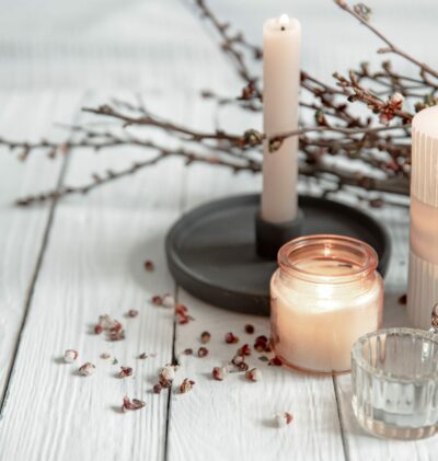 Cozy composition with flaming candles and young tree branches on a wooden surface in the Scandinavian style.